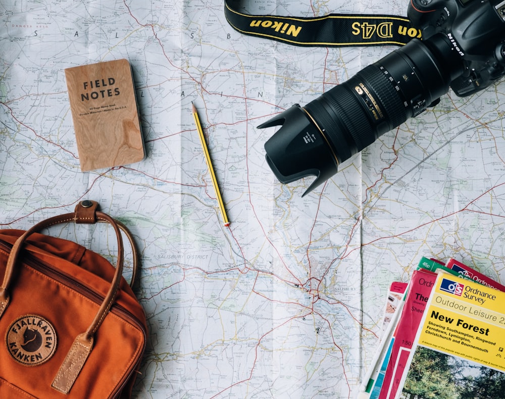 A high-quality, flat-lay composition of travel essentials scattered on a vintage world map.